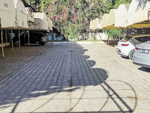 Ein gepflasterter Innenhof mit parkenden Autos und einem Baum mit rosa Blüten.