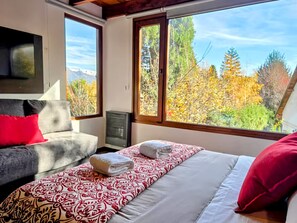Une chambre à coucher avec un lit, une chaise et une fenêtre donnant sur des arbres.