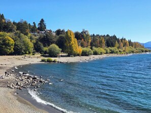 A beach with clear water, trees, and a distant mountain range. - #3 Monoambiente, buena vista, excelente wifi (San Carlos de Bariloche)