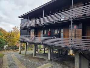 Un bâtiment à deux étages doté d’un balcon, de portes en bois et d’un téléphone rouge pour les urgences.
