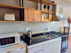 A modern kitchen with a built-in microwave, kettle, sink, and stove. - #3 Monoambiente, buena vista, excelente wifi (San Carlos de Bariloche)
