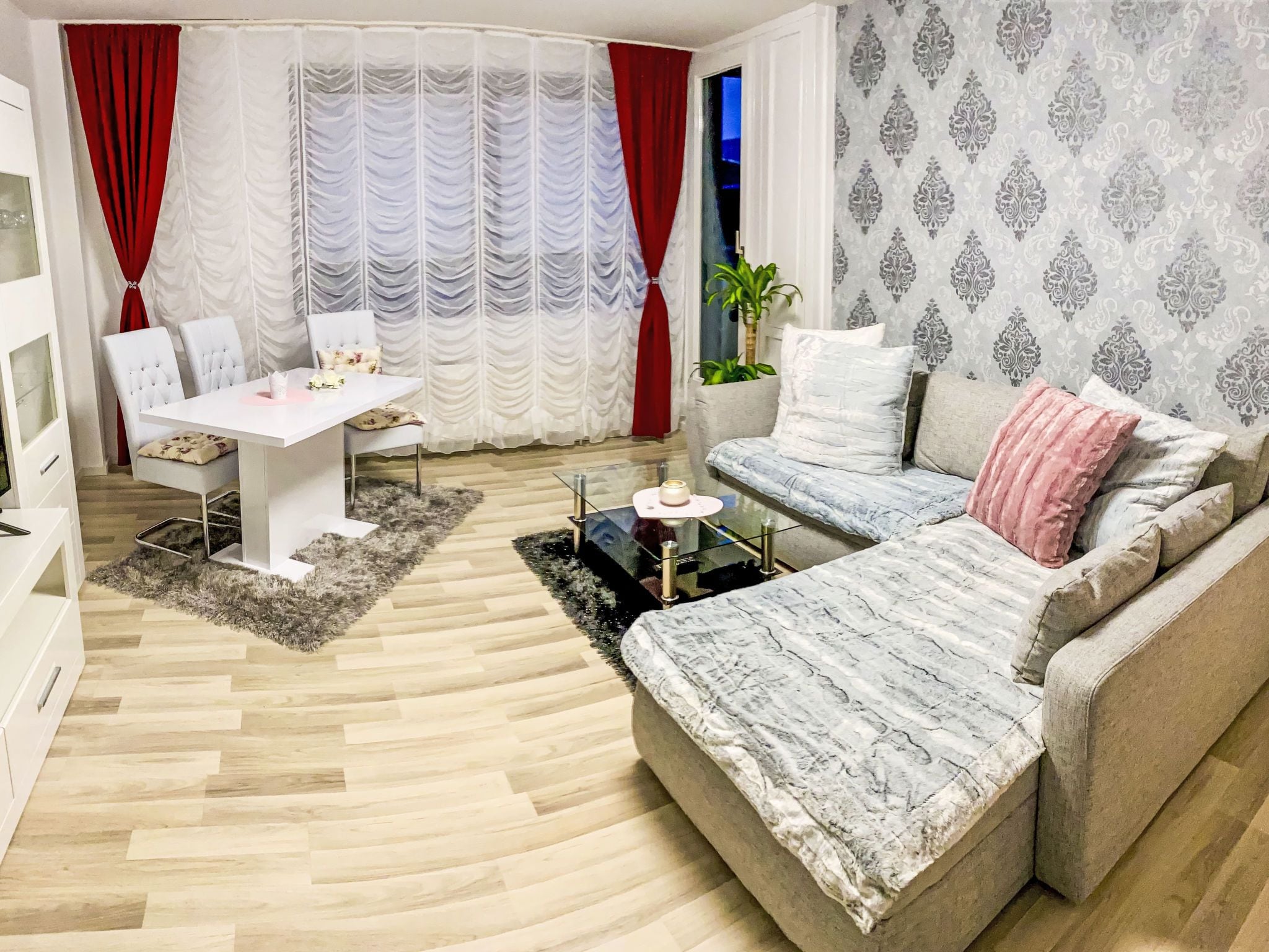 A modern living room with a sofa, a dining table, and a white cabinet.