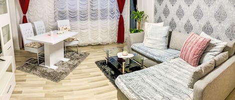 A modern living room with a sofa, a dining table, and a white cabinet.