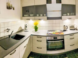 A kitchen with a sink, stove, oven, and a vase with flowers on the counter. - Maritime Perle Bremerhaven by Interhome (Bremerhaven)