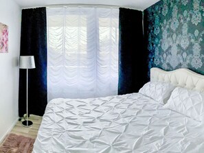 Ein Schlafzimmer mit einem Bett, Vorhängen, einer Lampe und einer Wand mit einem Blumenmuster.