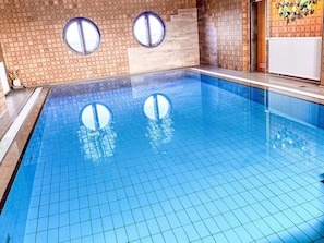 Ein Schwimmbecken mit gefliestem Boden und zwei runden Fenstern.