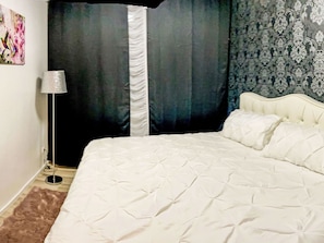 A bedroom with a bed, curtains, a lamp, and a patterned wall. - Maritime Perle Bremerhaven by Interhome (Bremerhaven)