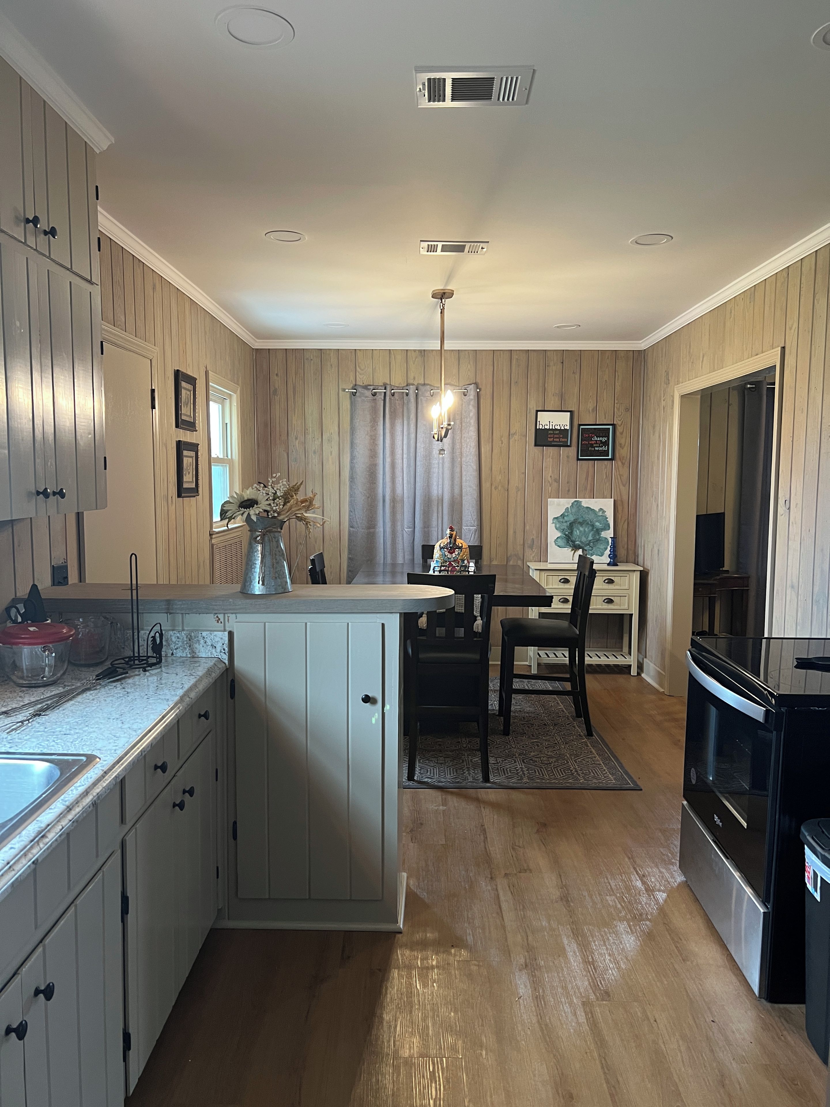 A kitchen with wooden cabinets, a dining area with a table and chairs, and a black stove.