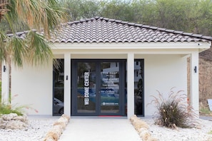 Ein Gebäude mit einem Ziegeldach und einem Eingang mit Glastür. An der Tür befindet sich ein Schild mit der Aufschrift 'WELCOME CENTER'.