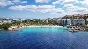 Ein Küstenresort mit Strand, Palmen und mehreren Hotelgebäuden.