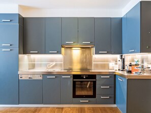 Une cuisine moderne avec des meubles gris, des appareils en acier inoxydable et un lave-vaisselle.