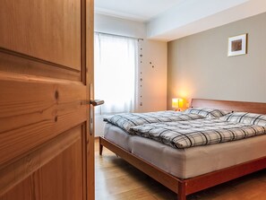 Ein Hotelzimmer mit einem hölzernen Bett, einer Nachttischlampe und einem Fenster mit Vorhängen.