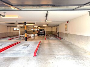 Un parking à plusieurs niveaux, avec des places de stationnement délimitées et une voiture garée au loin.