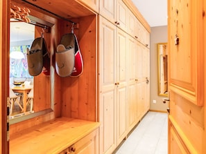 Een houten interieur met een bank, een spiegel en een garderobe met meerdere deuren.