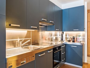 A modern kitchen with stainless steel appliances, dark cabinetry, and a built-in oven. - Chesa Altrova by Interhome (St. Moritz)