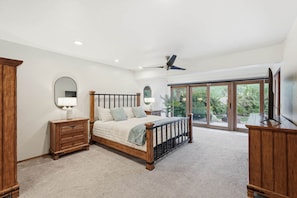 A bedroom with a large bed, wooden furniture, and a view through large windows. - The Retreat
at Bear Canyon (Tanque Verde)