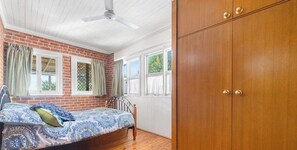 A bedroom with a bed, a wooden wardrobe, and a ceiling fan. - 84 On White - 4 bedroom with private pool & entertainer's deck (East Tamworth)