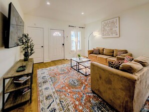 Ein Wohnzimmer mit Sofa, Couchtisch, Teppich und einem Gemälde an der Wand.