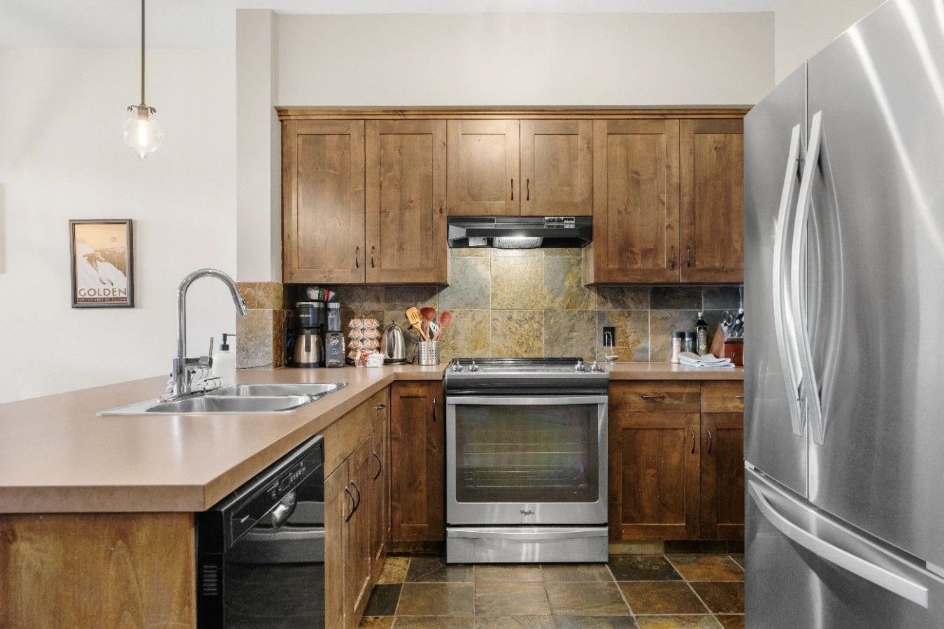 Une cuisine moderne avec des meubles en bois, des appareils électroménagers en acier inoxydable et un lave-vaisselle.