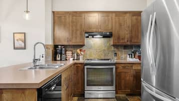 Une cuisine moderne avec des meubles en bois, des appareils électroménagers en acier inoxydable et un lave-vaisselle.