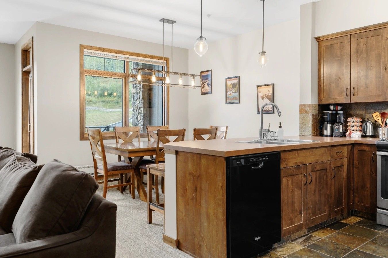 Une cuisine moderne avec des meubles en bois, un lave-vaisselle et un coin repas comprenant une table et des chaises.