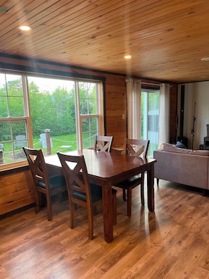 A wooden interior with a dining table, chairs, a sofa, and a kitchen area.