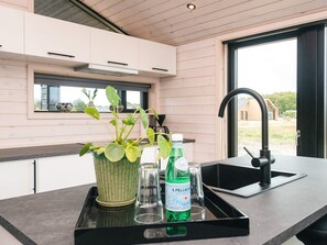 A modern kitchen with a black countertop, a window with a view, and a potted plant. - 5 Star Holiday Home in Romo (Rømø)