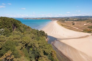Ein Strand mit freiem Blick auf die Küste, umgeben von dichtem Wald.