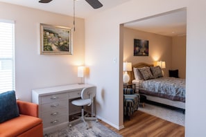 Une chambre à coucher avec un lit, des lampes de chevet, un bureau avec une chaise et un tableau au mur.
