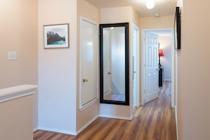Un couloir doté d’un plancher en bois, de murs blancs et d’une porte à cadre noir.