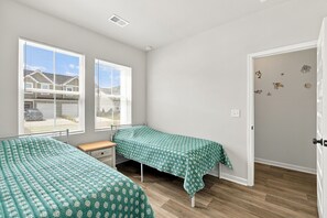 A bedroom with two beds, a window, and a door. - Brilliant 3-bedroom house with AC near ocean Isl Bch (OCEAN ISL BCH)