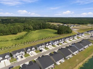 Una zona residencial con casas independientes, una avenida principal y un amplio campo verde.