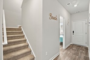 A hallway with carpeted stairs, a white door, and a wall-mounted sign. - Brilliant 3-bedroom house with AC near ocean Isl Bch (OCEAN ISL BCH)