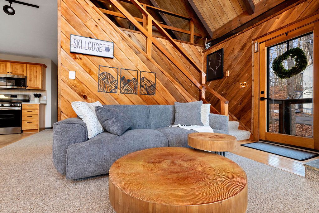 Ein gemütliches Wohnzimmer mit einer Eckcouch, Holzelementen und einem Schild mit der Aufschrift 'SKI LODGE'.
