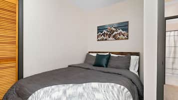Un dormitorio con una cama, un cuadro en la pared y una puerta de madera.