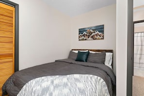 A bedroom with a bed, a painting on the wall, and a wooden door. - Blackrock Canopy (Nellysford)