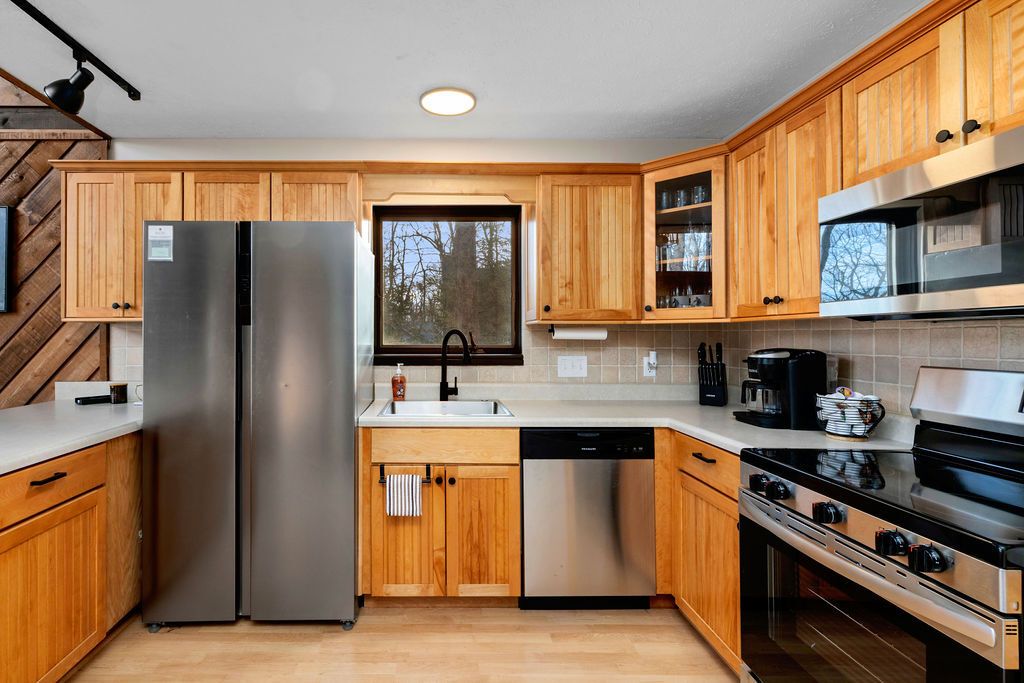 Una cocina moderna con armarios de madera, electrodomésticos de acero inoxidable y un ventanal que aporta luz natural.