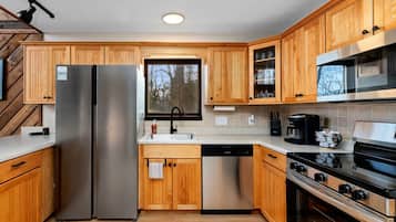 Una cocina moderna con armarios de madera, electrodomésticos de acero inoxidable y un ventanal que aporta luz natural.