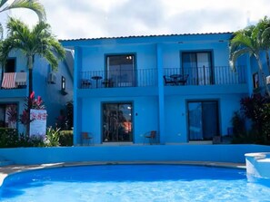 A two-story hotel with a swimming pool in front. - Villa Riviera 2BR Near the Beach (Coco)
