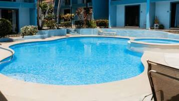 A swimming pool with a curved edge, surrounded by a concrete deck.