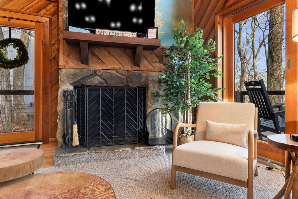 A cozy interior with a fireplace, a comfortable chair, and a view of the outdoors.