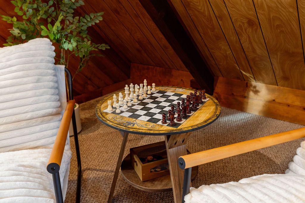 Ein Schachbrett auf einem kleinen Tisch in einem Zimmer mit Holzwänden und -decke.