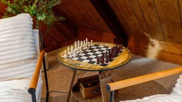 A chessboard on a small table in a room with wooden walls and a ceiling.