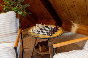Een schaakbord op een kleine tafel in een kamer met houten wanden en een plafond.