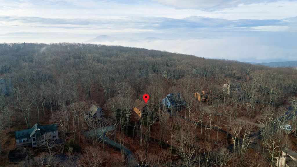 A forested area with a red marker, a building, and a winding path.
