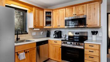 A modern kitchen with wooden cabinets, stainless steel appliances, and a dishwasher.
