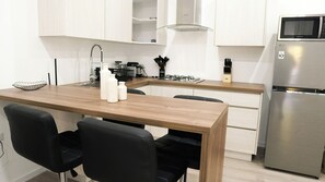 A modern kitchen with a wooden dining table, black chairs, a stainless steel refrigerator, and white cabinets. - Downtown Studio Walk to Beach CasaAmarilla 202 (Oranjestad)