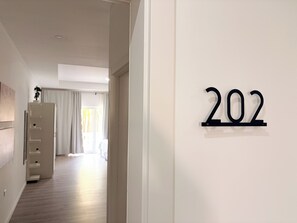 A hallway with a number sign '202' on the wall, a white wall, and a wooden floor. - Downtown Studio Walk to Beach CasaAmarilla 202 (Oranjestad)