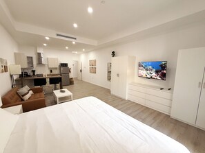 A modern hotel room with a large bed, a TV, a kitchenette, and a dining area. - Downtown Studio Walk to Beach CasaAmarilla 202 (Oranjestad)