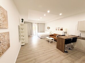 Ein modernes Hotelzimmer mit Bett, Sofa, Schreibtisch und Essbereich.